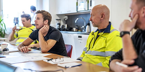 Anleggsarbeidere i møte på kontor