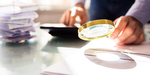 Person går igjennom økonomien med  lupe
