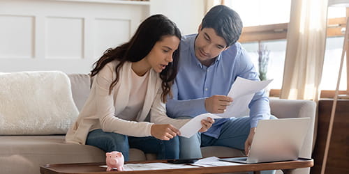 Et par sitter ned med papirer og pc for å ordne opp i økonomien