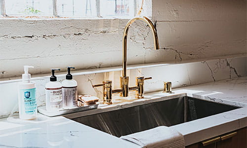 Kjøkkenbenk med forgylt armatur og marmorlignende benkeplate