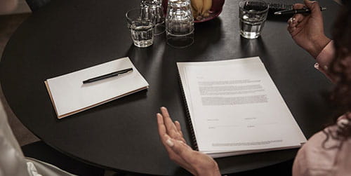 skrivebord med papirer, kvinne skal signere dokument